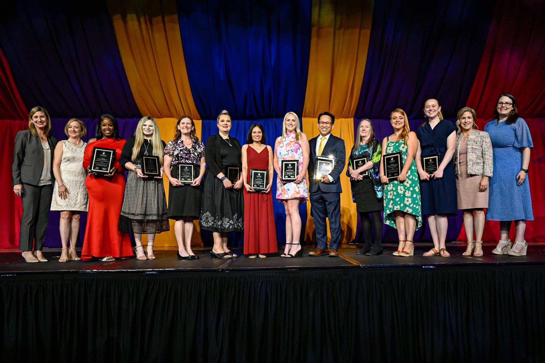 winning teachers with plaques on stage with board members and superintendent